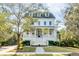 Charming two-story white home boasts a welcoming front porch and meticulously landscaped front yard at 217 King George St, Daniel Island, SC 29492