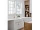 Farmhouse sink with elegant faucet, bright natural light, and white cabinets with brass hardware at 217 King George St, Daniel Island, SC 29492