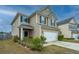 Two-story home with beige siding, black shutters, a two-car garage, and well-maintained landscaping at 252 Swamp Creek Ln, Moncks Corner, SC 29461
