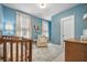 Cozy Bedroom with blue walls, curtains, a crib, and a comfortable armchair at 2710 Mcfadden Way, Johns Island, SC 29455