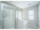 Bright bathroom featuring a glass enclosed shower and separate soaking tub beneath a window at 5150 Trump # 1904, North Charleston, SC 29420