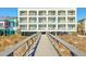 Condo complex with a wooden walkway leading to a multi-story building with balconies at 1126 Ocean Blvd # 109, Isle of Palms, SC 29451