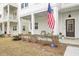 Close-up of inviting front porch with seating, American flag, and well-maintained landscaping at 129 Sabal Ct, Summerville, SC 29483