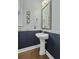 Elegant pedestal sink with framed mirror and dark blue wainscoting accents the powder room at 213 Crossandra Ave, Summerville, SC 29483