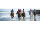 A group of people horseback riding on the beach with water splashing around them at 2653 Seabrook Island Rd, Seabrook Island, SC 29455