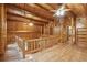 Spacious hallway with wood floors and wood plank walls, with an upper-level landing showcasing log beam construction at 415 W Carolina Ave, Summerville, SC 29483