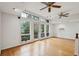 Bright living room features hardwood floors, two ceiling fans, and a wall of large windows with a wooded view at 415 W Carolina Ave, Summerville, SC 29483