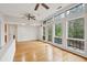 Bright living room features hardwood floors, two ceiling fans, and a wall of large windows with a wooded view at 415 W Carolina Ave, Summerville, SC 29483
