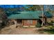 Exterior front view of log cabin featuring a green metal roof, small porch and mature trees at 120 Rancho Hippey Way, Saint George, SC 29477