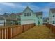 Backyard with freshly installed lawn, a wood privacy fence, and neighboring homes under a blue sky at 219 Corvus St, Summerville, SC 29483