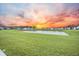 Expansive green space with a large pond reflecting a vibrant, colorful sunset at 296 Firewheel Ct, Summerville, SC 29486
