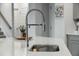 Close up on a kitchen sink with stainless steel faucet and quartz countertop with white cabinets and light fixtures at 296 Firewheel Ct, Summerville, SC 29486
