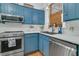 Close up of well-equipped kitchen, stainless appliances, blue cabinets and white subway tile at 301 E Richardson Ave, Summerville, SC 29483