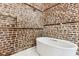 Bright bathroom featuring a white soaking tub and exposed brick walls at 31 Hasell St, Charleston, SC 29401
