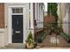 Elegant front entrance with a black door, white trim, gated entry and lush plantings at 31 Hasell St, Charleston, SC 29401
