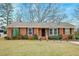 Charming brick home featuring a well-maintained lawn, trimmed bushes, and classic black shutters at 3351 Londonderry Rd, North Charleston, SC 29420