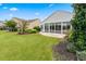 Manicured backyard with lush green lawn, mature landscaping, and enclosed sunroom at 550 Tidewater Chase Ln, Summerville, SC 29486