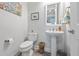 Bright powder room featuring a pedestal sink, framed mirror, wood-look floors and decorative artwork at 550 Tidewater Chase Ln, Summerville, SC 29486