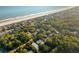 Aerial view of beachfront homes surrounded by verdant trees and oceanfront access at 608 W Beach Ct, Folly Beach, SC 29439