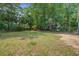 Lush backyard with mature trees, a sprawling lawn, and a quaint home exterior at 6094 Chisolm Rd, Johns Island, SC 29455