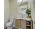 Bathroom with wood vanity, round mirror, white toilet, and light walls at 6094 Chisolm Rd, Johns Island, SC 29455