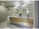 Modern bathroom featuring double sinks, wood cabinets, round mirrors, tiled shower and light walls at 6094 Chisolm Rd, Johns Island, SC 29455