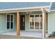 Covered back porch with stained wood columns, exterior windows, and a door at 64 Piedmont Rd, Walterboro, SC 29488