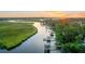 Scenic aerial view of a riverfront community with private docks, lush marshlands, and a vibrant sunset backdrop at 6917 Tanner Hall Blvd, Hanahan, SC 29410