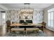 Beautiful dining room featuring a long table with bench seating, stylish chandelier, and patterned wallpaper at 6917 Tanner Hall Blvd, Hanahan, SC 29410