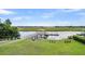 Beautiful waterfront view with a covered dock, wooden walkway, and benches on the lush green lawn at 6917 Tanner Hall Blvd, Hanahan, SC 29410