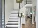Elegant foyer featuring hardwood floors, staircase with contrasting black and white, and view into living room at 6917 Tanner Hall Blvd, Hanahan, SC 29410