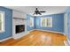Living room featuring bright blue walls, brick fireplace, and gleaming hardwood floors at 7537 Parkers Ferry Rd, Adams Run, SC 29426