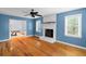 Living room featuring bright blue walls, brick fireplace, and gleaming hardwood floors at 7537 Parkers Ferry Rd, Adams Run, SC 29426