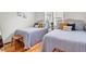 Cozy bedroom with two twin wicker beds with blue striped linens and hardwood floors and a woven stool at 783 Lake Frances Dr, Charleston, SC 29412