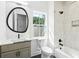 Modern bathroom featuring a sleek vanity with a round mirror, white subway tile shower, and a sunlit window at 916 Kincade Dr, Mount Pleasant, SC 29464