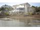 View of a tan home with white trim, elevated with a screened porch and stairs at 10 Toms Turnaround Cir, Edisto Island, SC 29438