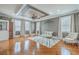 This living room has a ceiling fan, tray ceilings, and wood flooring with lots of natural light at 1012 Denali Ct, Summerville, SC 29483