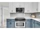 Well-equipped kitchen with stainless steel range, microwave, white countertops, and blue lower cabinets at 1106 Mccrae Dr, Moncks Corner, SC 29461