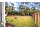 Large, well-maintained backyard with wooden fence, green grass, a stone fire pit, and mature landscaping at 1502 Checker Ct, Mount Pleasant, SC 29466