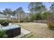 Backyard with a wooden fence, a concrete patio with seating, and surrounded by tall trees at 2025 Lanneau Ln, Johns Island, SC 29455