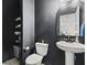Modern half bathroom with black walls, pedestal sink, round mirror and storage shelving at 2025 Lanneau Ln, Johns Island, SC 29455