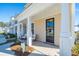Inviting front porch with seating, columns, and view of manicured landscaping and neighboring townhomes at 207 Abercom Place Dr, Moncks Corner, SC 29461