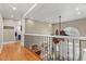 Bright hallway featuring hardwood floors, detailed trim, and railing overlooking the living room with a unique ceiling fan at 2786 Parkers Landing Rd, Mount Pleasant, SC 29466