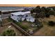 Aerial view of fenced backyard featuring a firepit, picnic table, and outdoor seating near palm trees at 407 Palmetto Blvd, Edisto Beach, SC 29438