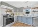 Kitchen with stainless steel appliances, light wood floors, and unique gray and blue cabinetry at 407 Palmetto Blvd, Edisto Beach, SC 29438