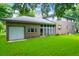 View of the home's back exterior, with a two-car garage and sunroom, surrounded by mature trees and a lush lawn at 652 E Hobcaw Dr, Mount Pleasant, SC 29464