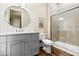 Bright bathroom features wood-look floors, a gray vanity, round mirror, and glass-enclosed shower at 112 E Huron Ave # C, Folly Beach, SC 29439