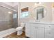 Bright bathroom features modern vanity, large round mirror, glass-enclosed shower, and a window at 112 E Huron Ave # C, Folly Beach, SC 29439