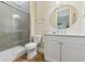 Bright bathroom features modern vanity, large round mirror, glass-enclosed shower, and updated flooring at 112 E Huron Ave # C, Folly Beach, SC 29439