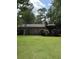 Manicured backyard featuring a brick home, a small white dog, green lawn, and outdoor deck at 125 Azalea Dr, Summerville, SC 29485